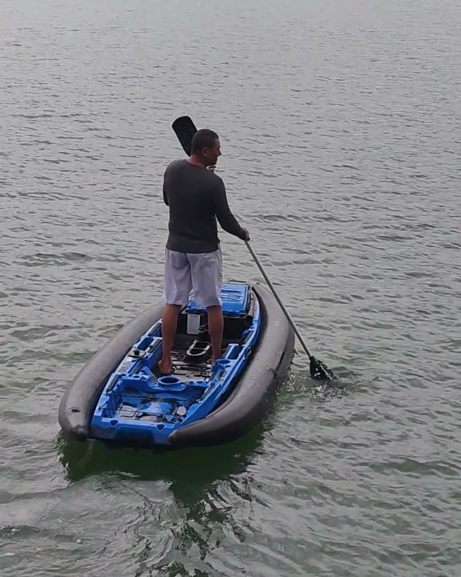 Flutuador inflável cinza envolvendo o casco de caiaque azul, visto de trás